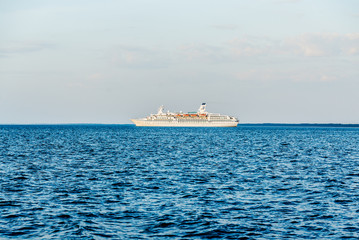 Clear blue sky. Large white passenger ship and a pilot boat in the Baltic Sea, close-up. Latvia