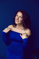 beautiful woman in long blue dress in Studio with blue wall