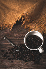 beans coffee in white cup on ancient wooden table background,roasted coffee beans grinded on an old wooden background