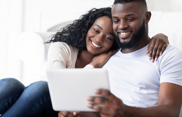 Afro couple browsing social media on digital tablet at home