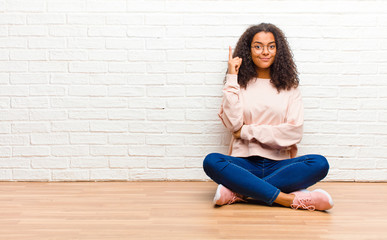 young african american black woman feeling like a genius holding finger proudly up in the air after...