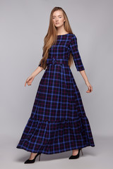 Full shot of a walking young blonde European lady with long hair in a black maxi dress with a print...