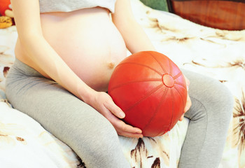  Teenage pregnancy is pregnancy in human females under the age of 20. Pregnant woman holding sport ball