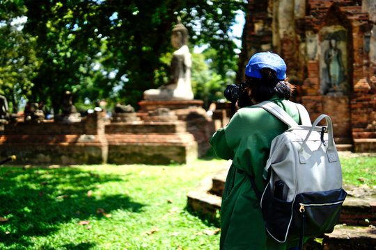  Asian female tourists taking pictures of Buddha images while traveling in the historic sites of Asia.