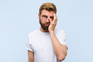 young blonde adult man feeling bored, frustrated and sleepy after a tiresome, dull and tedious...
