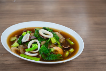 Fried noodle with pork ,Kale Seafood, shrimp, squid in cup on wooden table.Thai food