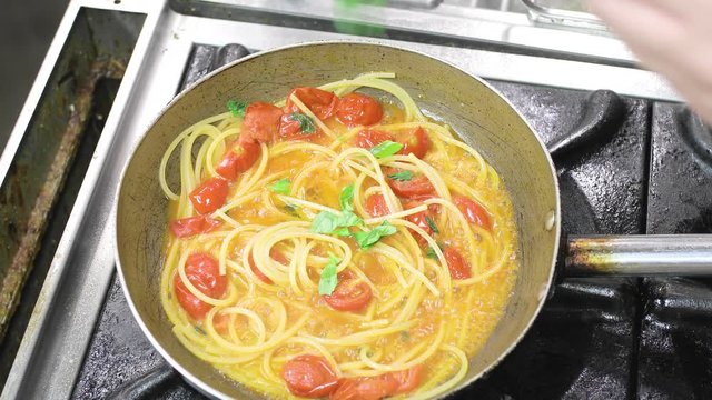 Spaghetti con pomodorini e basilico nella cucina di un ristorante.