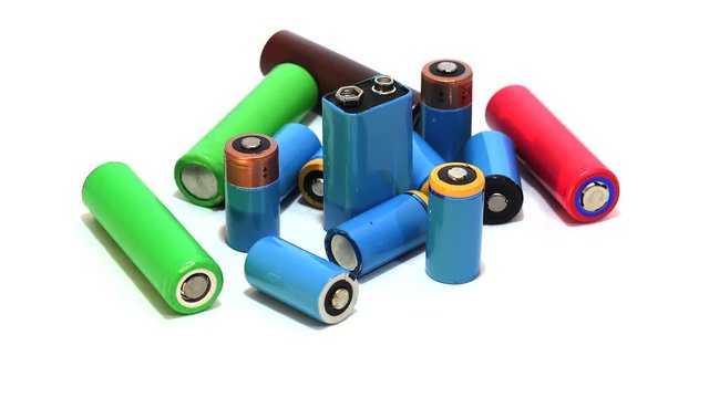 Different types of disposable & rechargeable batteries rotating on white.