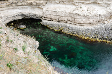 Bay among the rocks. Clear water, through which you can see the bottom of the sea.