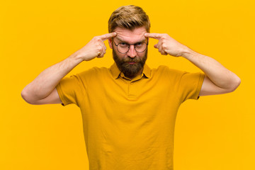 young blonde man with a serious and concentrated look, brainstorming and thinking about a...