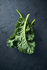 Fresh green kale leaves on dark stone background. Healthy food ingredients