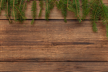 Fur spruce pine coniferous branches on the brown brushed wooden background