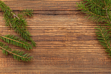 Fur spruce pine coniferous branches on the brown brushed wooden background