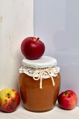 Homemade seasonal preparations. Beautifully packaged jars of apple jam. Covered with paper and tied with a cord. Nearby are fresh apples.