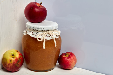 Homemade seasonal preparations. Beautifully packaged jars of apple jam. Covered with paper and tied with a cord. Nearby are fresh apples.
