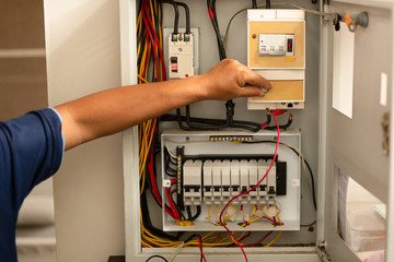 Senior electrician measuring voltage in fuse board.
