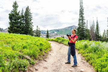Albion Basin, Utah summer with man taking pictures of landscape view of dirt road trail up in...