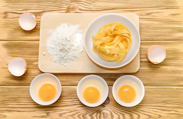 finished pasta next to flour and egg on a wooden table. pasta and ingredients.