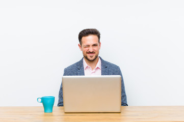 young handsome businessman looking happy and friendly, smiling and winking an eye at you with a...