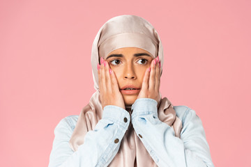 scared muslim girl in hijab, isolated on pink