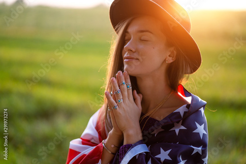 Portrait of boho chic woman in hat with american flag wearing silver rings with turquoise stone at sunset. Jewelry indie girl with hippie style and boho fashion. Travel to america