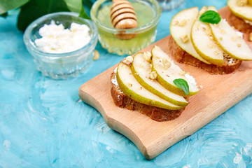 Bruschetta and Crostini with pear, ricotta cheese, honey, nuts and herbs. Breakfast toasts or snack sandwiches. Antipasto. Italian food. Copy space.