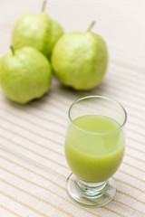 Glass of Guava Smoothie with blurred guava fruit background.