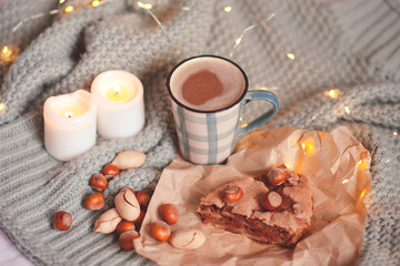 Charlotte pie with nuts, cup of coffee and burning candles in bed staying on knitted cloth close up. Good morning. Autumn season.