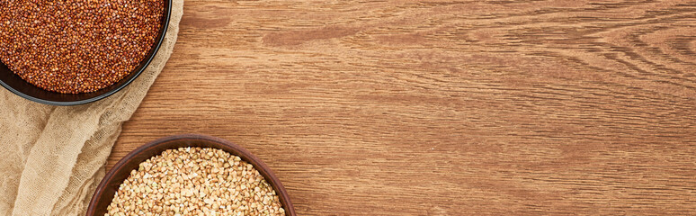 panoramic shot of bowls with diverse buckwheat on wooden surface with canvas