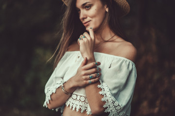Beautiful fashionable boho chic woman in straw hat and in a white short blouse with silver...