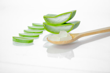 Aloe vera fresh leaves with slices and gel on wooden spoon on white background.