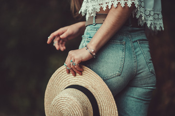 Stylish fashion woman in jeans shorts and in a white short blouse with silver turquoise rings holds...