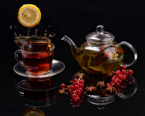 Teapot and a cup of tea from a glass on a  black background