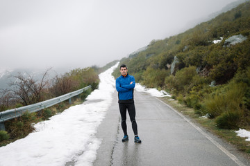 Athlete taking a break during winter outdoor workout on mountain road.