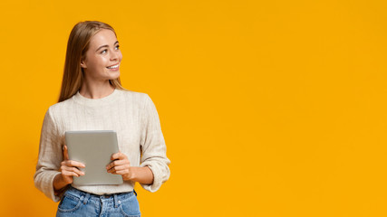 Beautiful girl holding digital tablet and looking at copy space