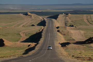 Empty small road in the dessert location country with one car is running.