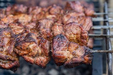 Grilled kebab cooking on metal skewer closeup. Roasted meat cooked at barbecue. BBQ fresh beef meat chop slices. Traditional eastern dish, shish kebab