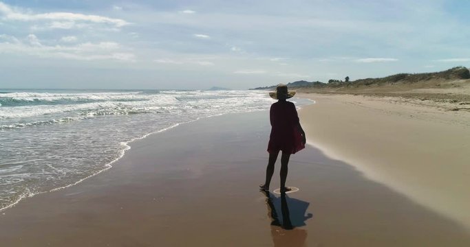 Mujer gira feliz en una playa de arena gravado por dron