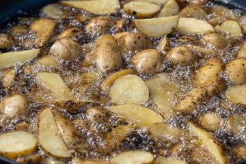 Roast potatoes in a large pan.Young potatoes are fried in oil, street food
