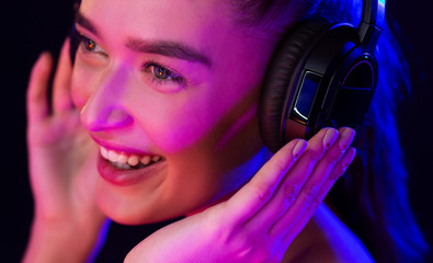 Happy woman with headset illuminated by neon lights