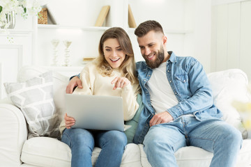 Fototapeta premium Happy couple using laptop and choosing film for watch