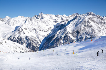 Skiers skiing downhill, Tirol (Tyrol) Austria. Big Alps panorama. Winter day.