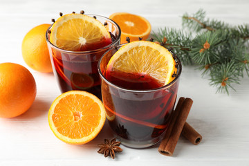 Glasses of tasty mulled wine with orange on white wooden background, close up