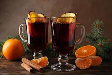 Glasses of tasty mulled wine with orange on wooden background, space for text