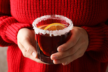 Girl in red sweater holding glass with mulled wine, close up