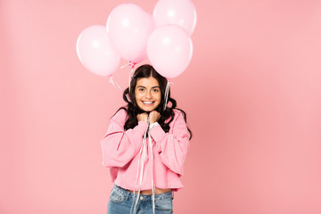 excited girl holding pink balloons, isolated on pink
