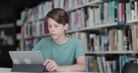 High school male student studying with digital tablet in library - Powered by Adobe