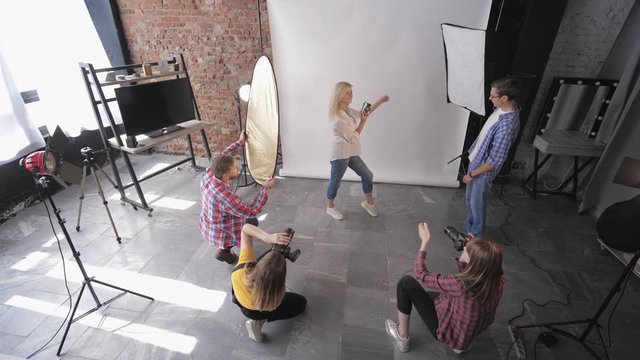 photographer with assistants working in a professional studio during a fashion session on background of lighting lamps, photo workshop