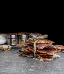 Dried meat slices with spices in jars, copy space