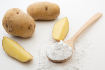 Close-up of potato starch or flour powder in wooden spoon on white background